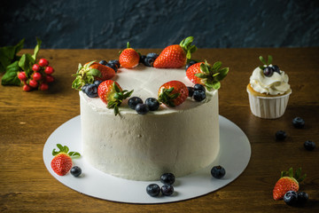 Delisious cakes with cream and berries an the dark stone background.