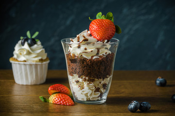 Delisious cakes with cream and berries an the dark stone background.