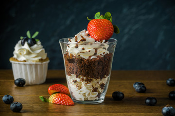 Delisious cakes with cream and berries an the dark stone background.