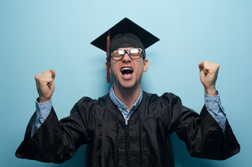 Excited caucasian man in graduation gowns raising hands