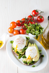 Avocado toast, cherry tomato on wooden background. Breakfast with toast avocado, vegetarian food, healthy diet concept. Healthy sandwich with avocado and poached eggs.