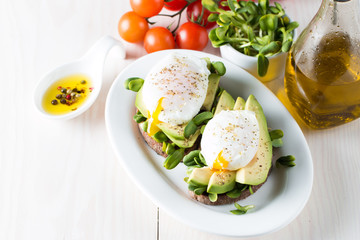 Avocado toast, cherry tomato on wooden background. Breakfast with toast avocado, vegetarian food, healthy diet concept. Healthy sandwich with avocado and poached eggs.