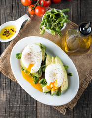 Avocado toast, cherry tomato on wooden background. Breakfast with toast avocado, vegetarian food, healthy diet concept. Healthy sandwich with avocado and poached eggs.