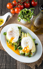 Avocado toast, cherry tomato on wooden background. Breakfast with toast avocado, vegetarian food, healthy diet concept. Healthy sandwich with avocado and poached eggs.