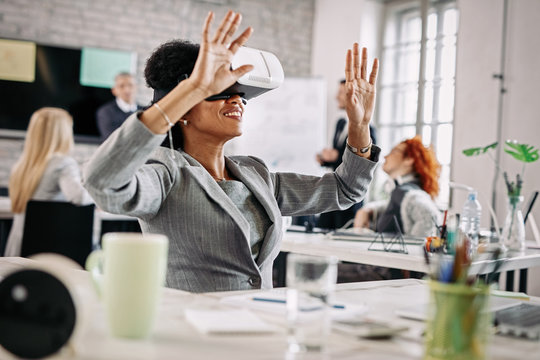 African American businesswoman having fun with virtual reality goggles at work.