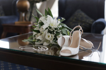 white lily bride bouquet, necklace, earrings, shoes on the table