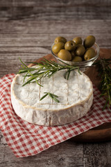 Brie type of cheese. Camembert cheese. Fresh Brie cheese and a slice on a wooden board with nuts, honey and leaves. Italian, French cheese.