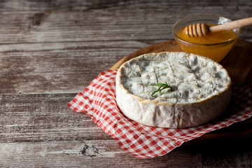 Brie type of cheese. Camembert cheese. Fresh Brie cheese and a slice on a wooden board with nuts, honey and leaves. Italian, French cheese.