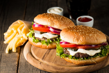 Close-up photo of home made hamburger with beer made of beef, onion, tomato, lettuce, cheese and spices. Fresh burger closeup on wooden rustic table with potato fries and chips.