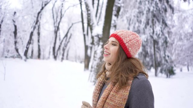 4k. Winter beauty.Pretty   young  woman in red hat  walking  in park.