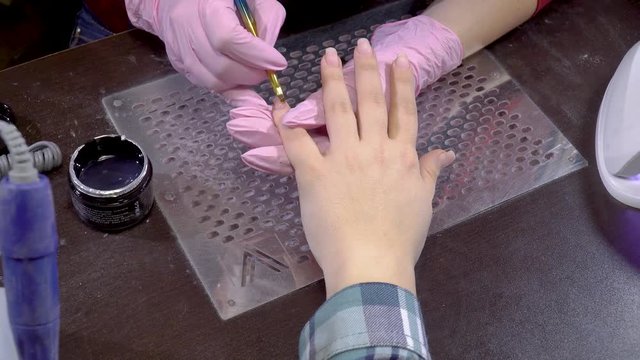 manicure master opens  jar of base gel and puts it on  nails  client, beauty salon