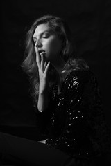 Portrait of beautiful sexy woman with luxurious curly hair in elegant black jacket with rhinestones posing in studio. Black and white vogue portrait