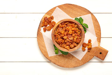 Raisins on wooden board white green leaf. 