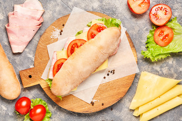 Sandwich baguette on chopping wooden board on white background. 