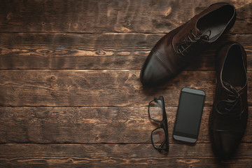 Businessman accessories such as mobile phone with a blank screen, glasses and a elegant shoes on a...