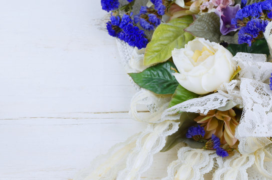 A variety of silk and dried flowers combines with lace is a feminine image good for anniversary, wedding, mother's day or birthday. Soft pastel colors with a pop of purple on wooden background