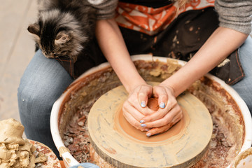 Happy woman working on potter wheel in pottery workshop. Family business shop sculpts pot from clay view top.