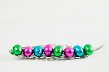 Colorful easter eggs on plastic silver feather on textured background