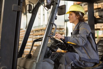 Young brunette female wearing in gray uniform and yellow helmet,  driving and making operating on...