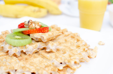 Desayuno saludable - waffles de harina del negrito, servidos con nueces, kiwi, fresas, banana y jugo fresco