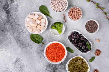 Superfoods on a gray background with copy space. Nuts, beans, greens and seeds. Healthy vegan food