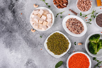 Superfoods on a gray background with copy space. Nuts, beans, greens and seeds. Healthy vegan food