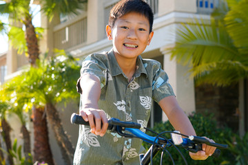 Young Asian boy on his bike in front of the house. Young teen boy on his bike smiling and showing...