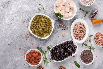 Superfoods on a gray background with copy space. Nuts, beans, greens and seeds. Healthy vegan food