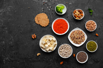 Superfoods on a gray background with copy space. Nuts, beans, greens and seeds. Healthy vegan food