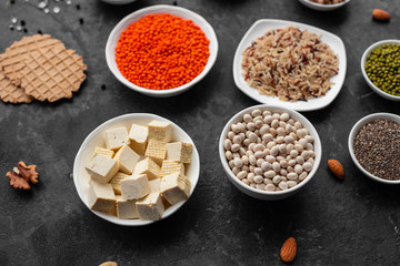 Superfoods on a gray background with copy space. Nuts, beans, greens and seeds. Healthy vegan food