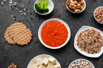 Superfoods on a gray background with copy space. Nuts, beans, greens and seeds. Healthy vegan food