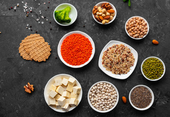 Superfoods on a gray background with copy space. Nuts, beans, greens and seeds. Healthy vegan food
