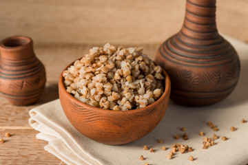 Cooked buckwheat cereal in brown clay bowl on wooden table. gluten free grain for healthy diet