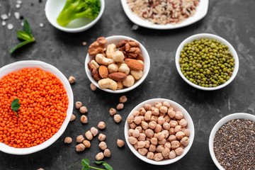 Superfoods on a gray background with copy space. Nuts, beans, greens and seeds. Healthy vegan food