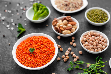 Superfoods on a gray background with copy space. Nuts, beans, greens and seeds. Healthy vegan food