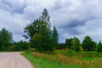 Country road on the outskirts of a field in the village. The photo was taken in Latvia.