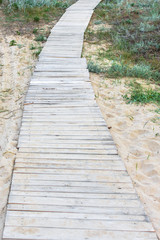 Obraz premium Wooden background. Boards in the sand. Wooden walkway on the sandy beach. Natural materials. The texture of the wooden surface. Beach landscape.