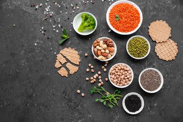 Superfoods on a gray background with copy space. Nuts, beans, greens and seeds. Healthy vegan food