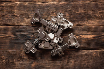 Door hinges on a wooden table background. Top view. - obrazy, fototapety, plakaty