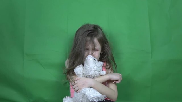 The little girl is crying and holding a soft toy.
