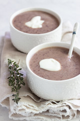 Cream soup with cauliflower and red bean served with sour cream and thyme. Light grey concrete background. Copy space. Comfort food.