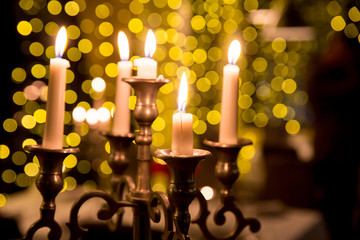 Candles to a beautiful candlestick.  Candles lighting in the dark night with bulbs lights in blur