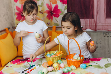 Two cute pretty preschool girl prepare easter eggs, drawing eggs together. Friendship, childhood, easter concept