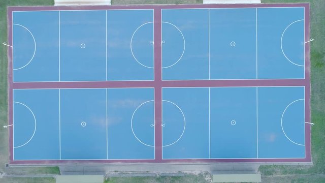 Slow aerial rise looking straight down at blue netball courts