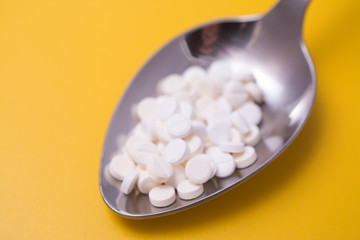 Fototapeta na wymiar medicine tablets on a spoon isolate on yellow background