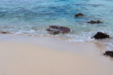 bright aqua water of the caribbean with rocks in the surf and pure clean sandy beach