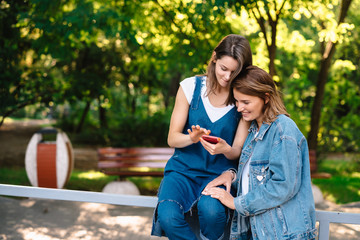 Fototapeta premium Two female girlfriends look at the smartphone at the pack