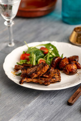 Lamb chops on a plate with vegetables and some potatoes.​