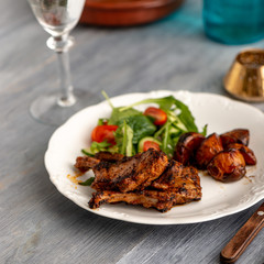 Lamb chops on a plate with vegetables and some potatoes.​