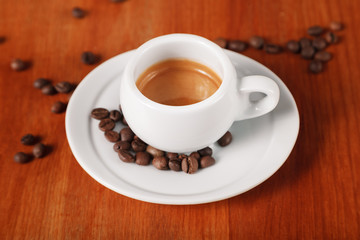 White espresso coffee Cup closeup, roasted coffee beans on wooden background. Concept of coffee break and serving coffee